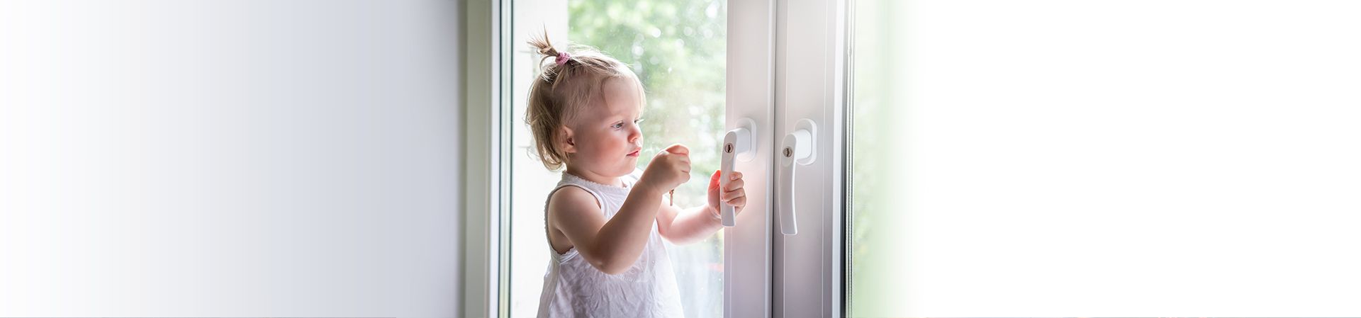 Kind mit Schlüssel vor abschließbaren Sicherheitsfenstern